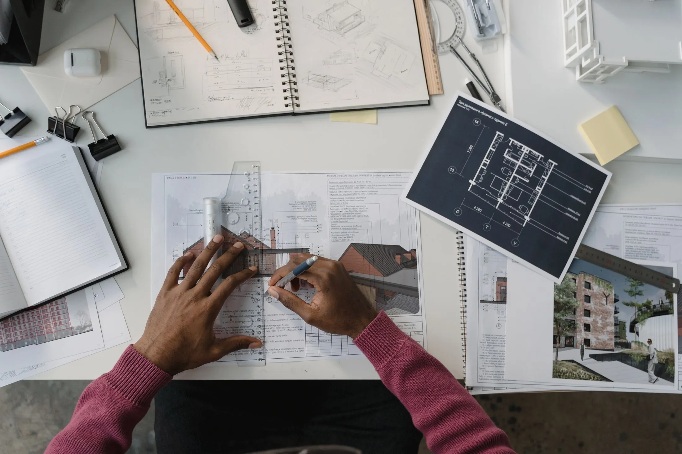An architect drawing plans at a desk covered in drafts and drawings