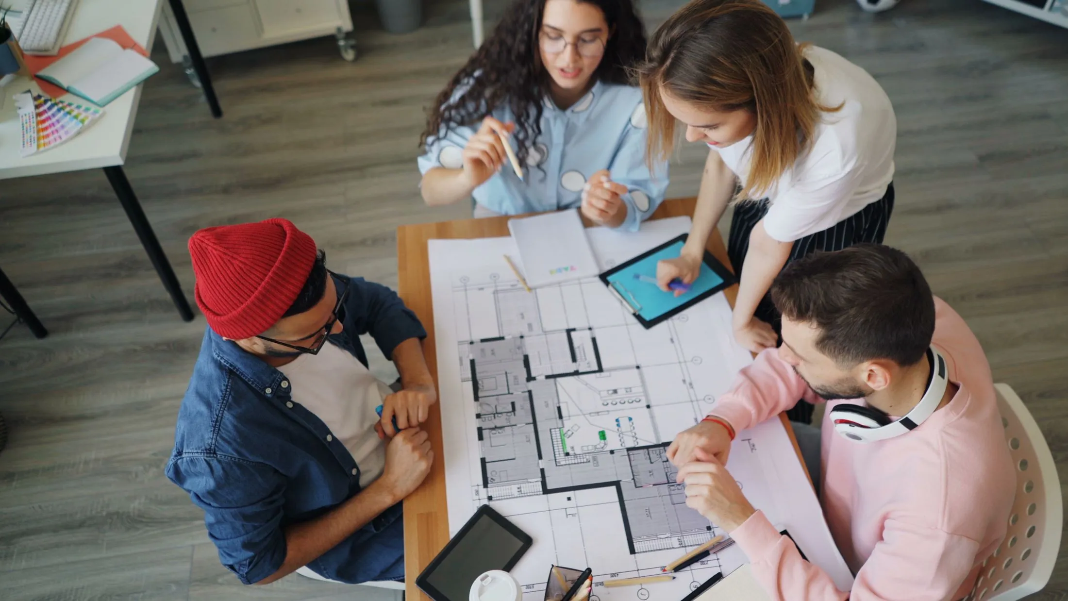 A team working through floor plans around a table, seen from above