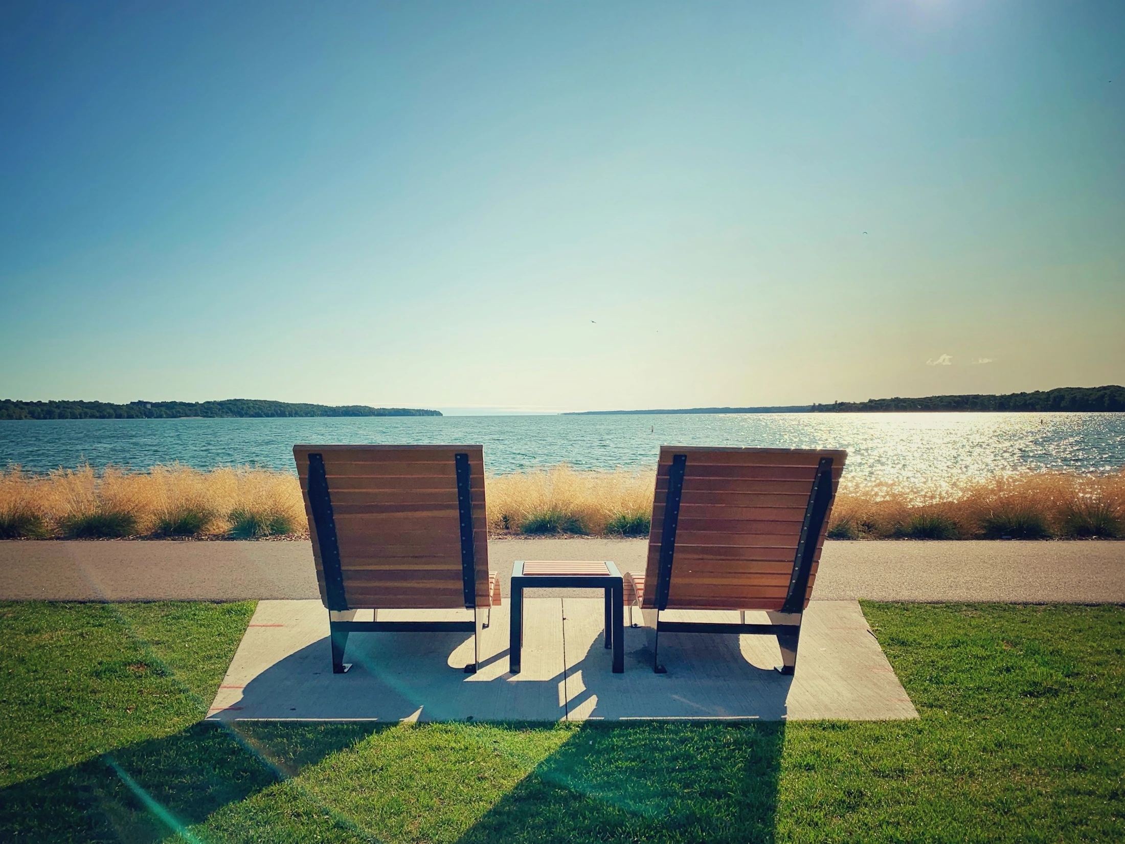 Two wooden lounge chairs facing Kempenfelt Bay along Barrie's waterfront