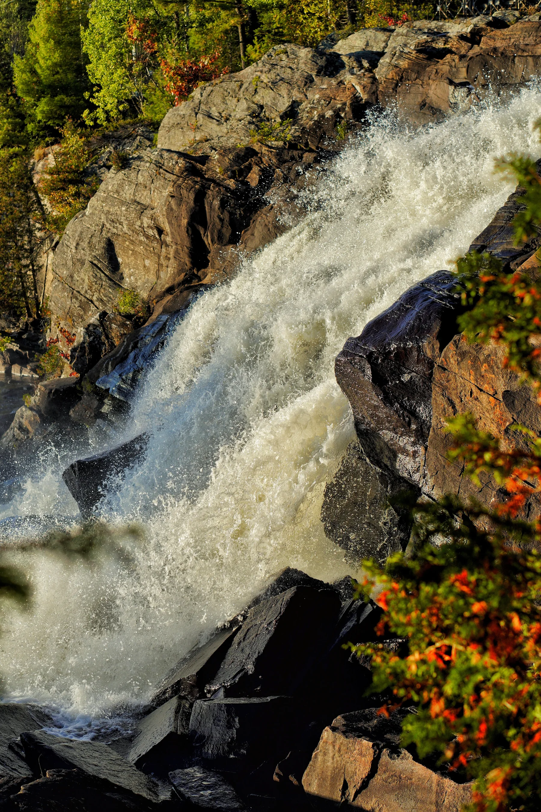 Close-up of Bracebridge Falls crashing over rocks in fall colour