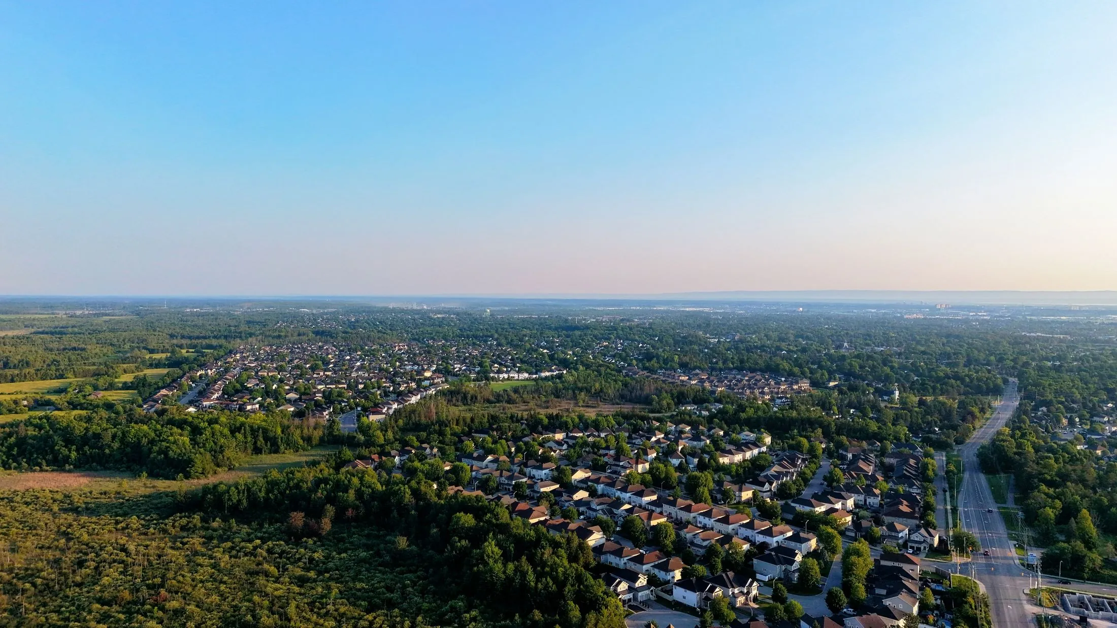 An aerial view of a neighbourhood meeting a stretch of green forest