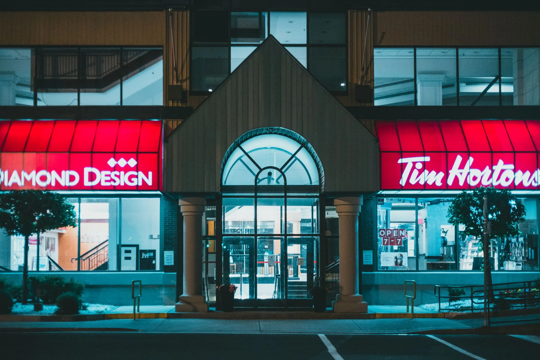 A coffee shop and storefronts lit up at night