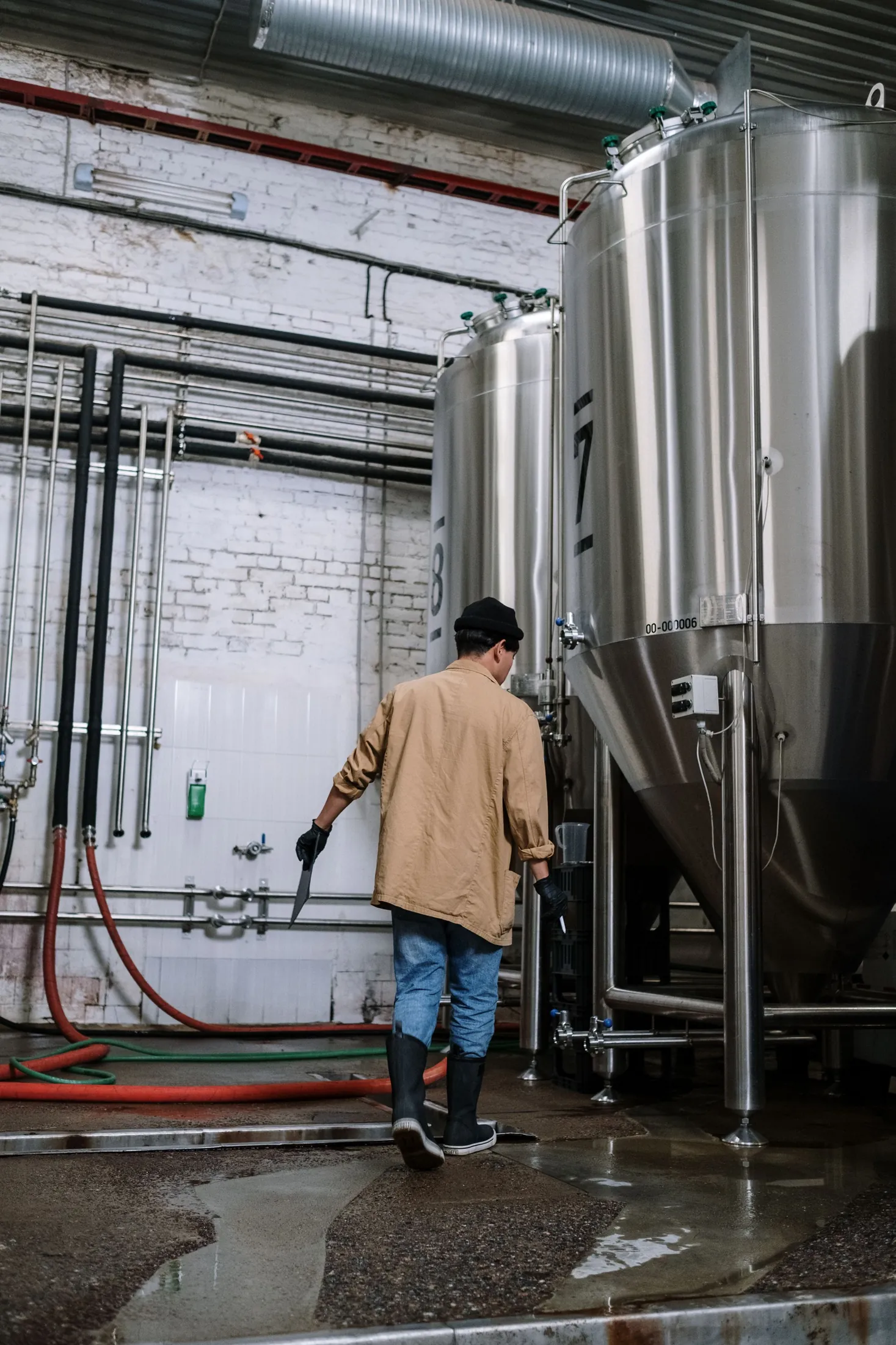 A brewer at work beside stainless steel fermentation tanks