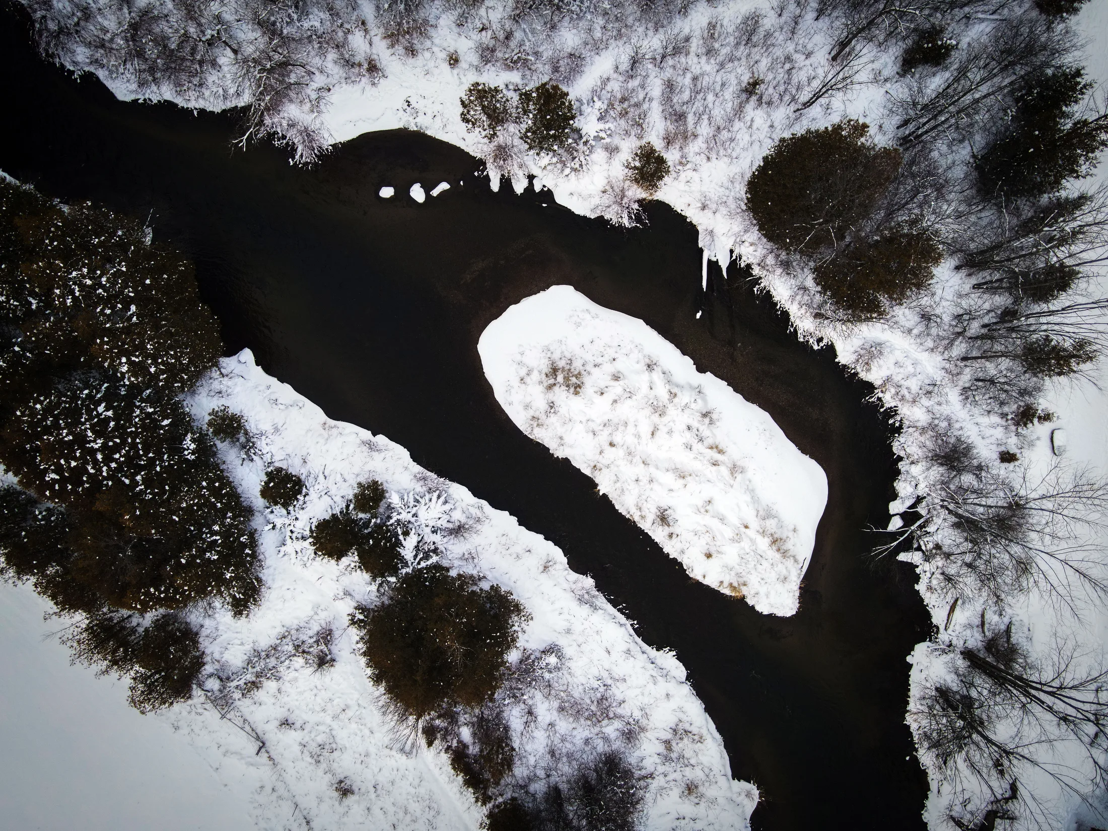 A snow-lined river winding through Caledon forest, seen from above