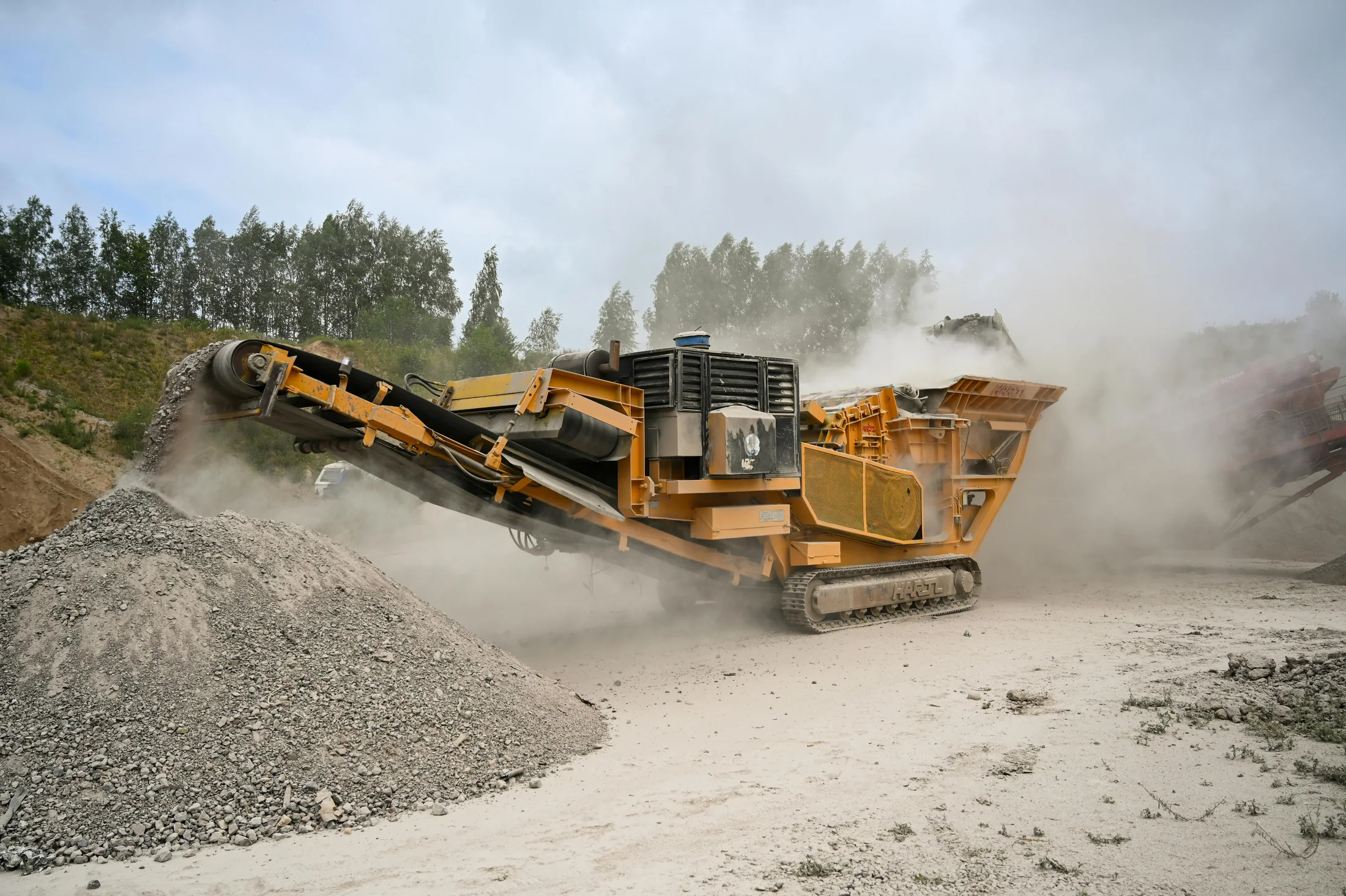 A rock crusher machine working through dust on a quarry site