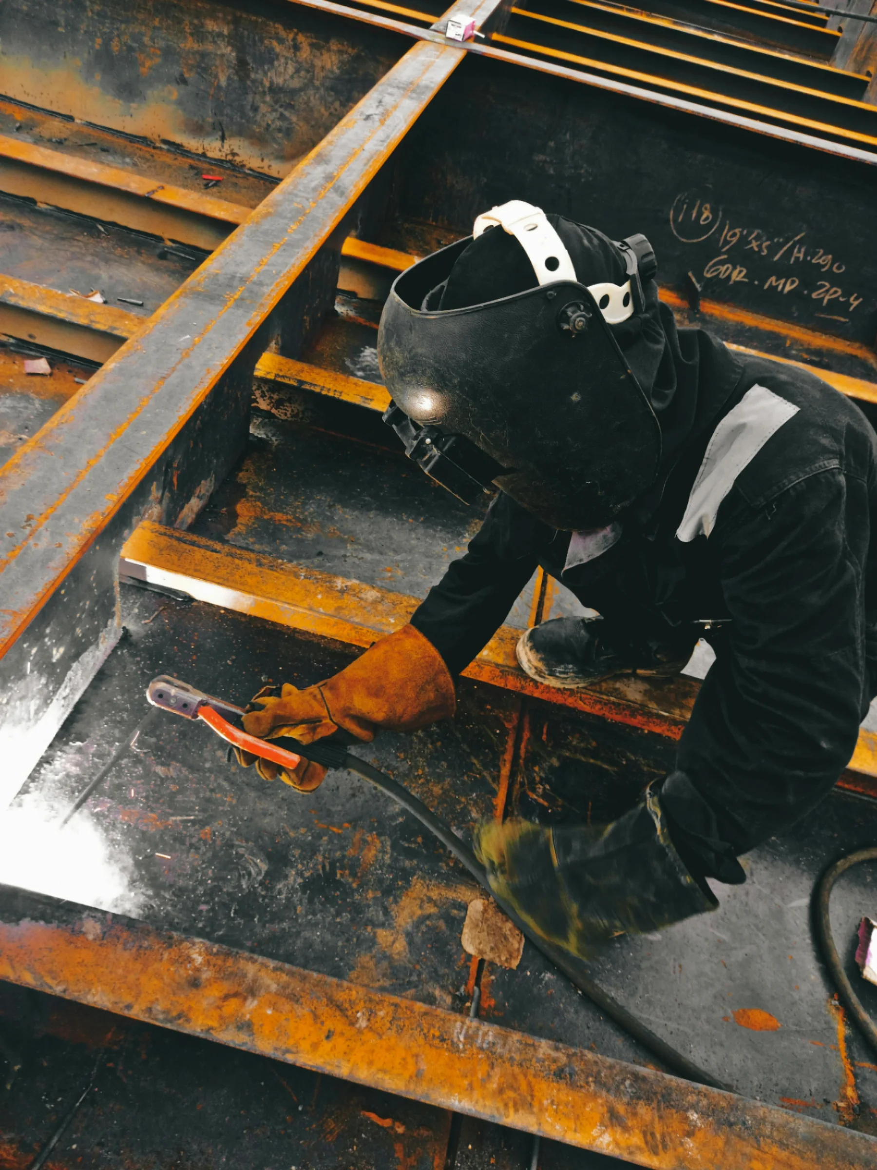 A welder at work, sparks flying, wearing full protective gear