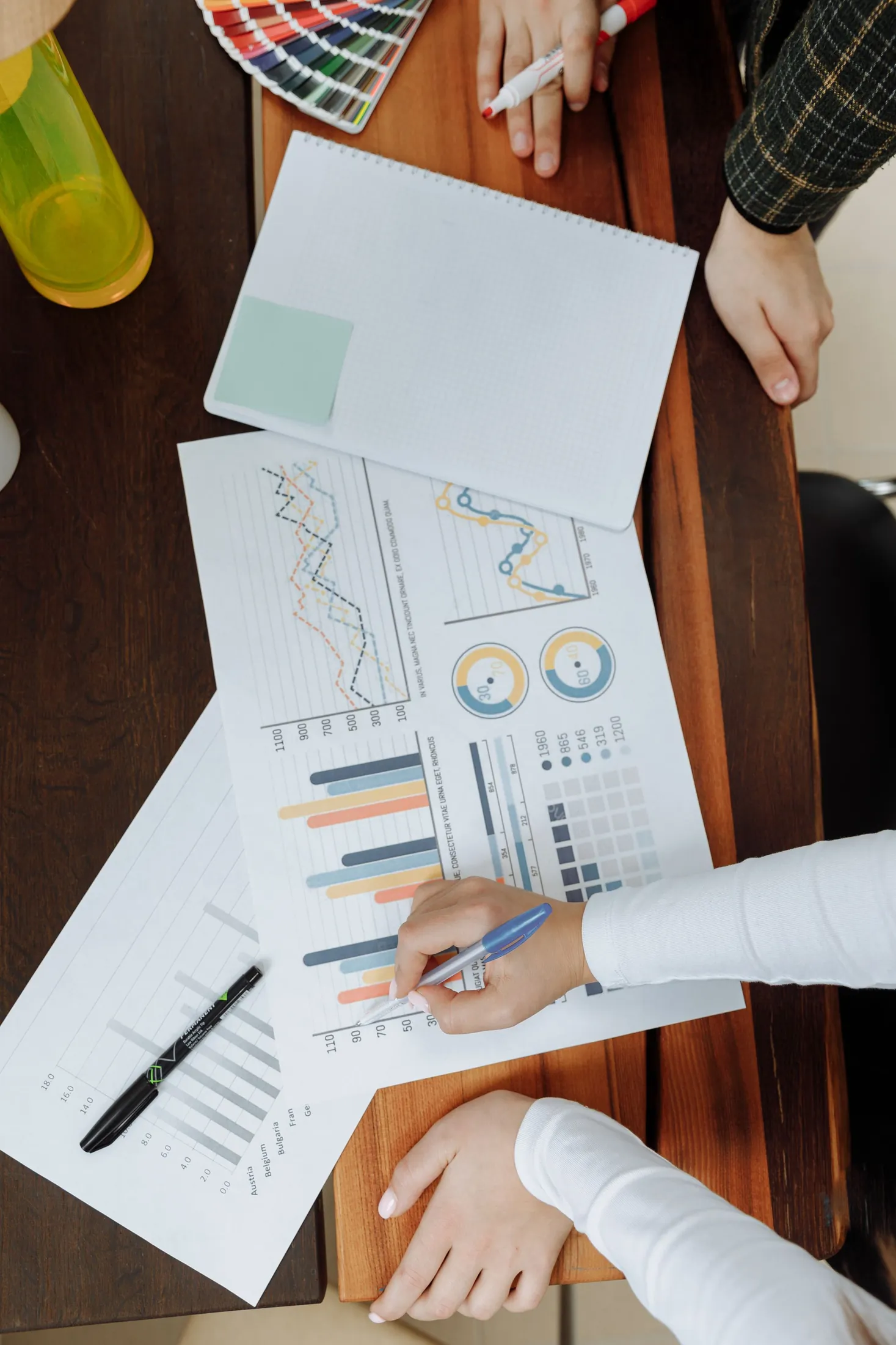 A team working through charts and diagrams on paper, seen from above