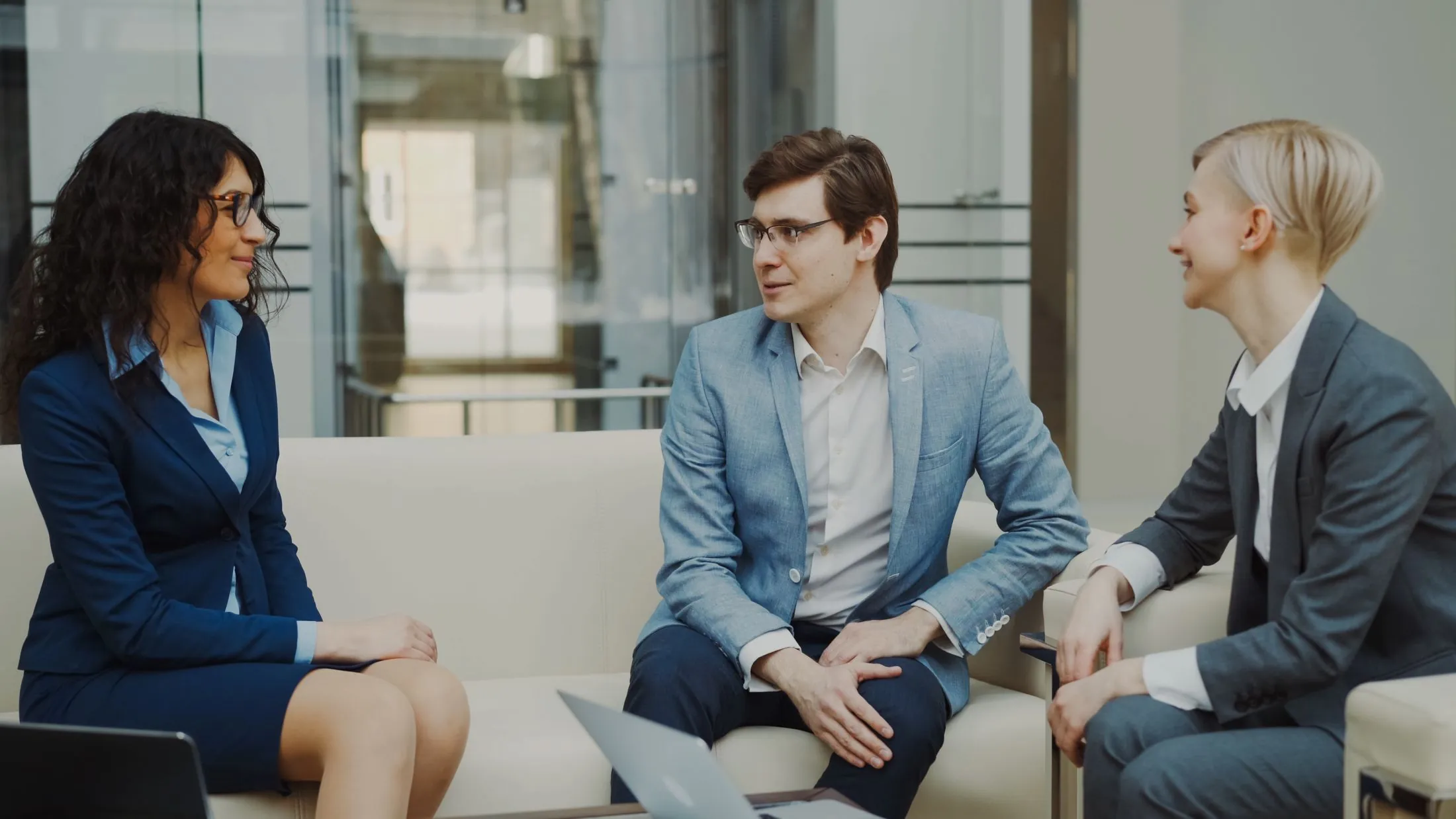 Three professionals in a meeting in a bright office lounge