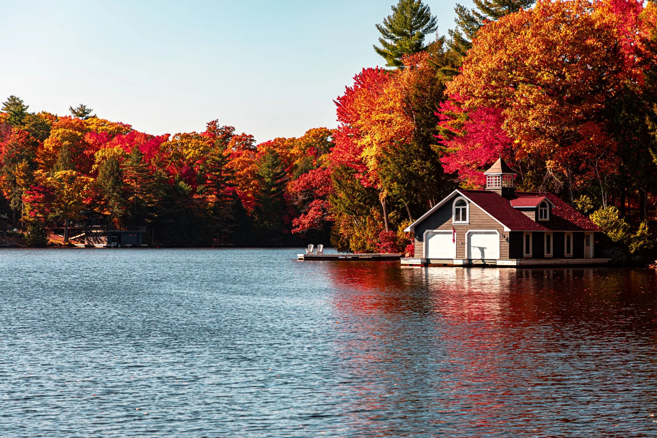A lakeside cottage and boathouse surrounded by fall colour in Ontario