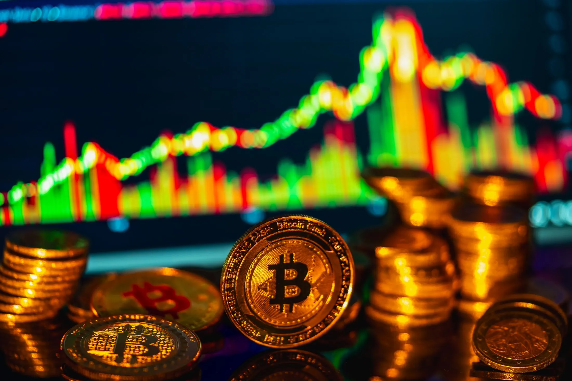 Gold Bitcoin coins stacked in front of a glowing market chart