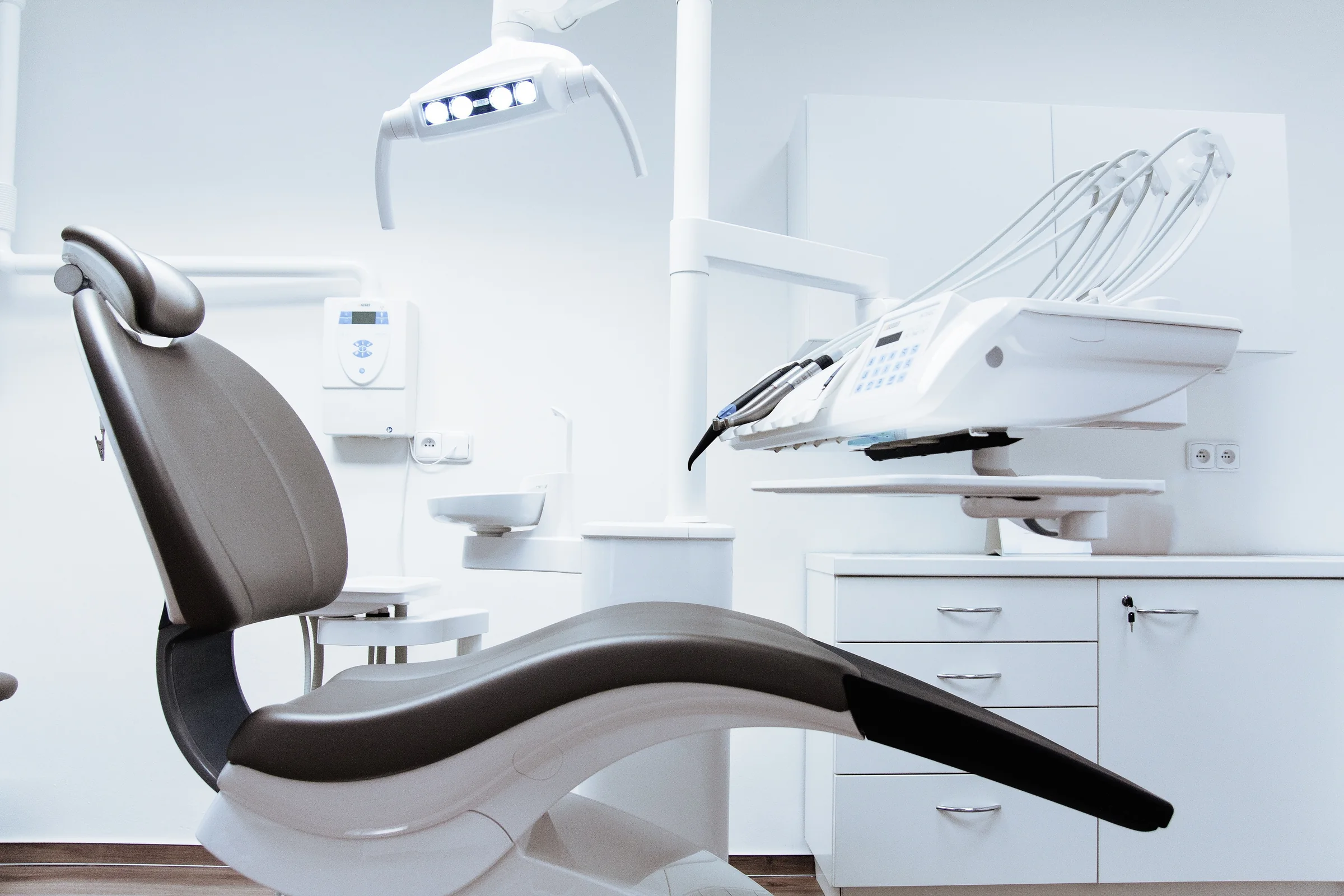A clean, modern dental operatory with an overhead light and chair, ready for a patient