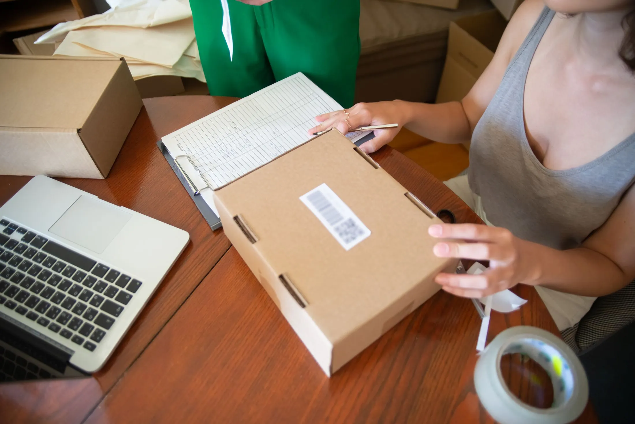 Packing an online order into a box beside a laptop