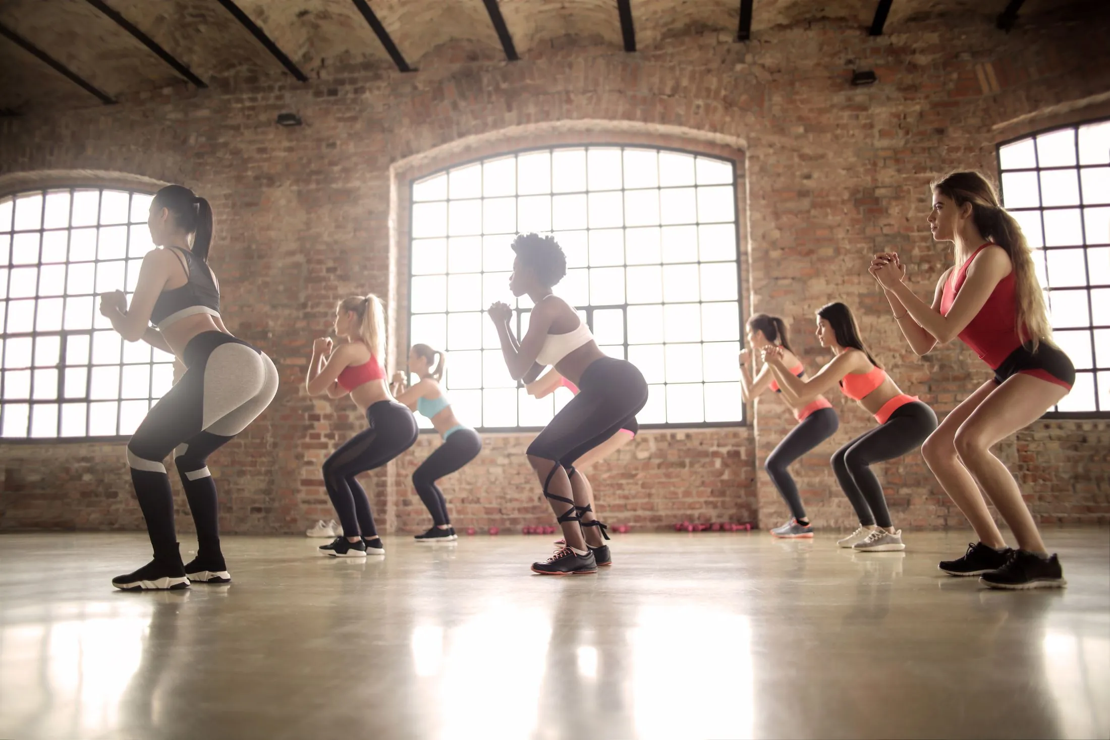 A group fitness class doing squats in a brick-walled studio