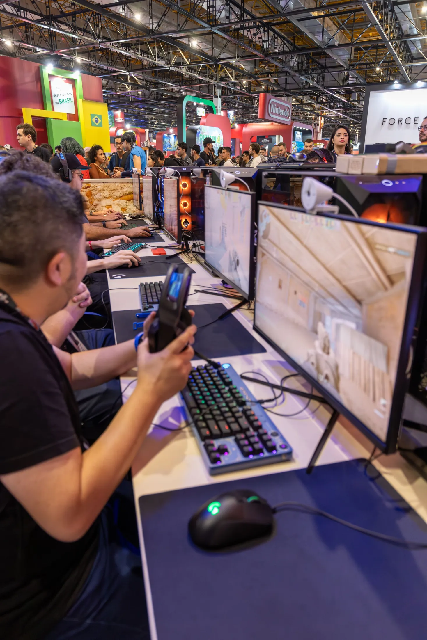 Players at gaming PCs on the floor of a busy gaming convention