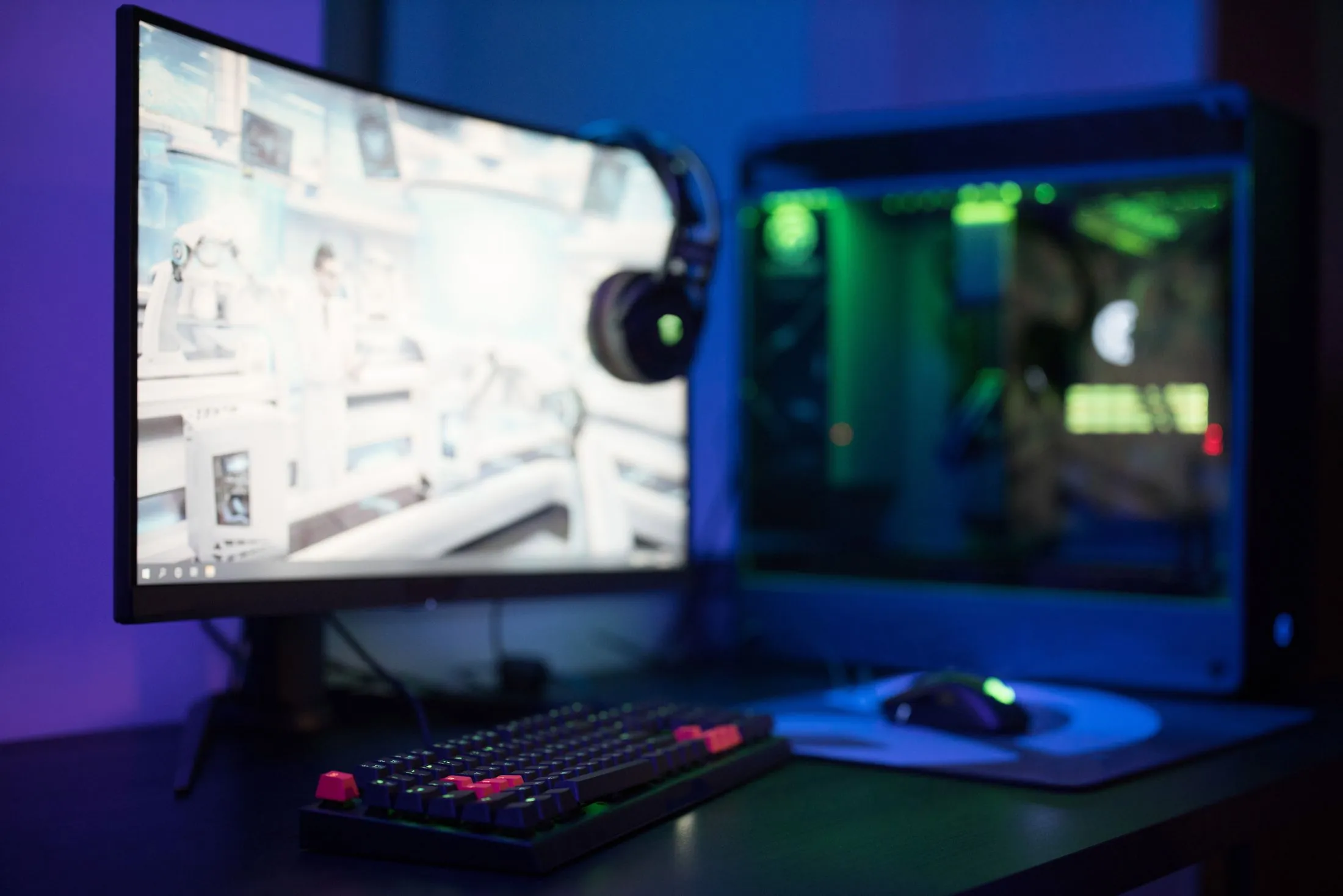 A curved monitor and a gaming PC glowing blue and green