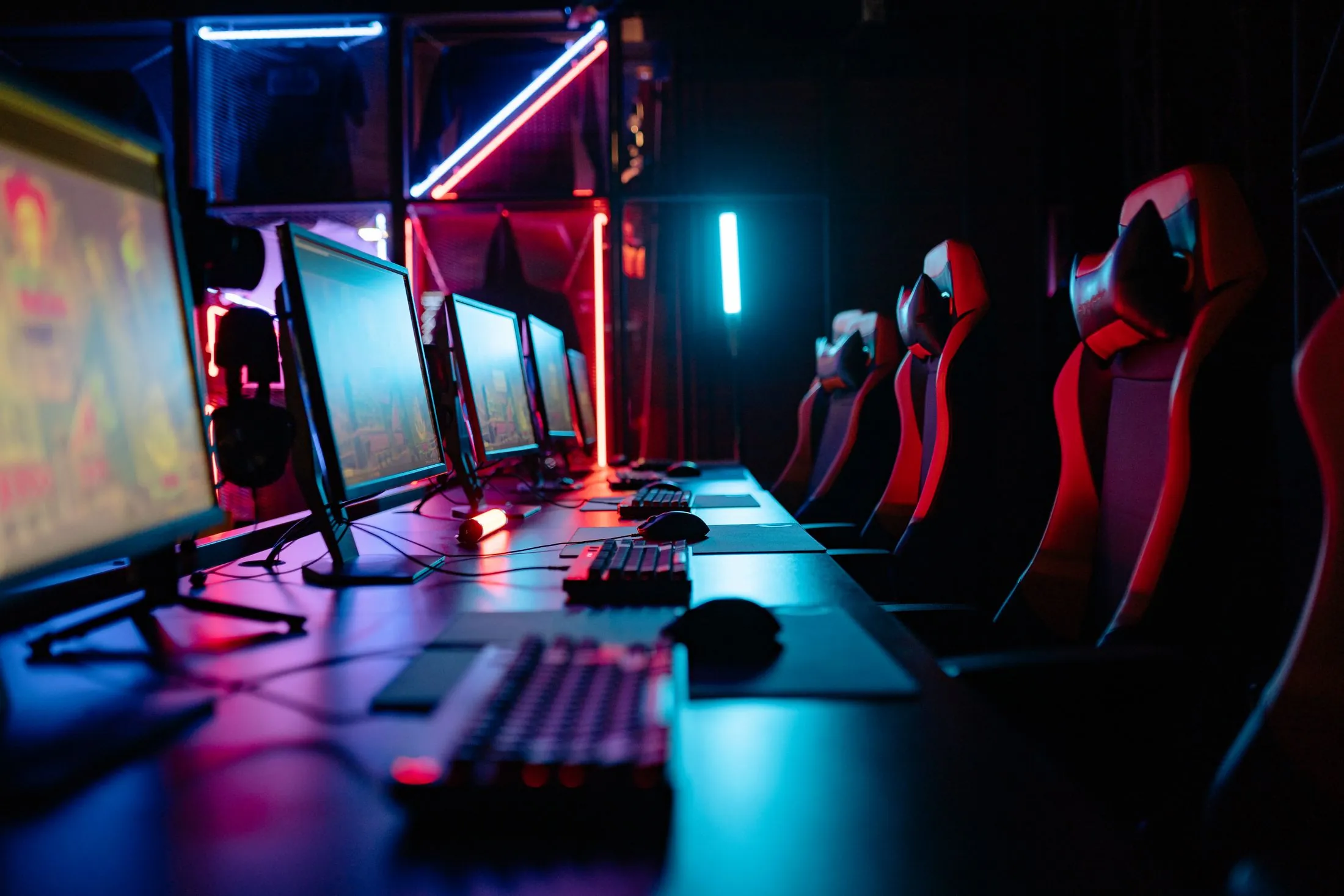 A row of gaming PCs and chairs lit in neon, ready for a tournament