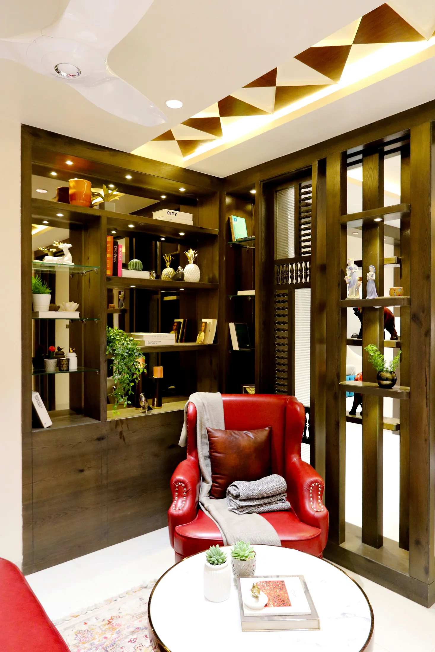 A red armchair beside built-in wooden shelving