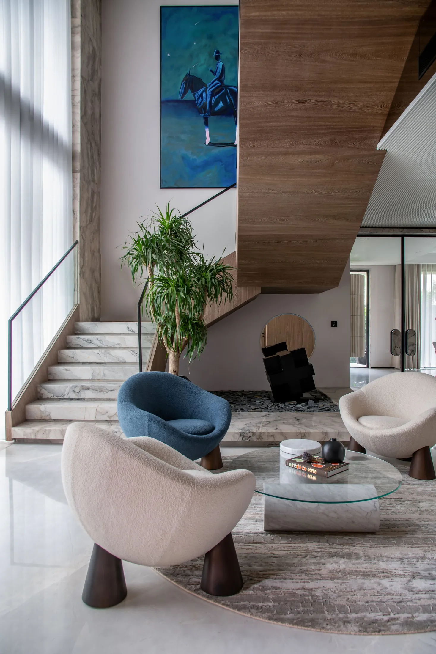 A modern living room with sculptural chairs, art and a wooden staircase