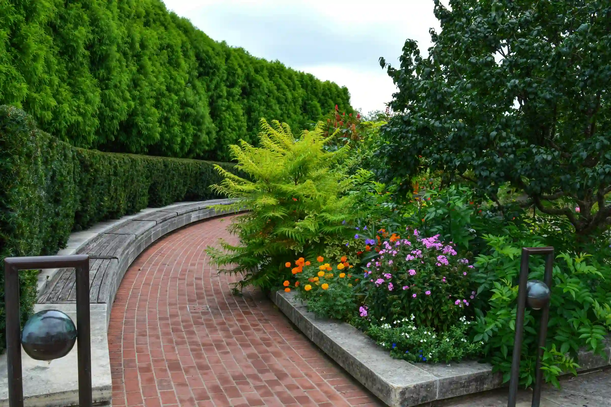 A curved brick garden path lined with trimmed hedges