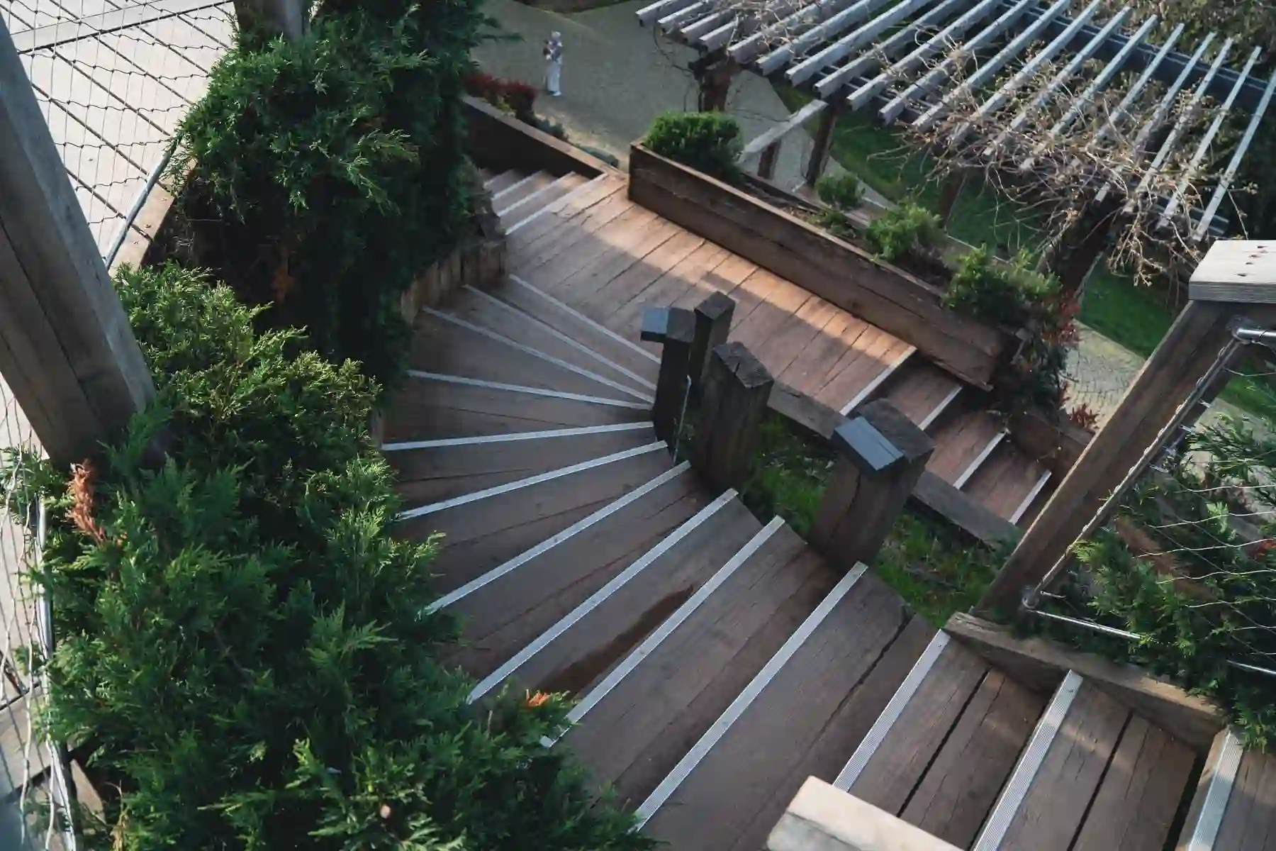 An aerial view of a wooden deck staircase winding through a landscaped yard