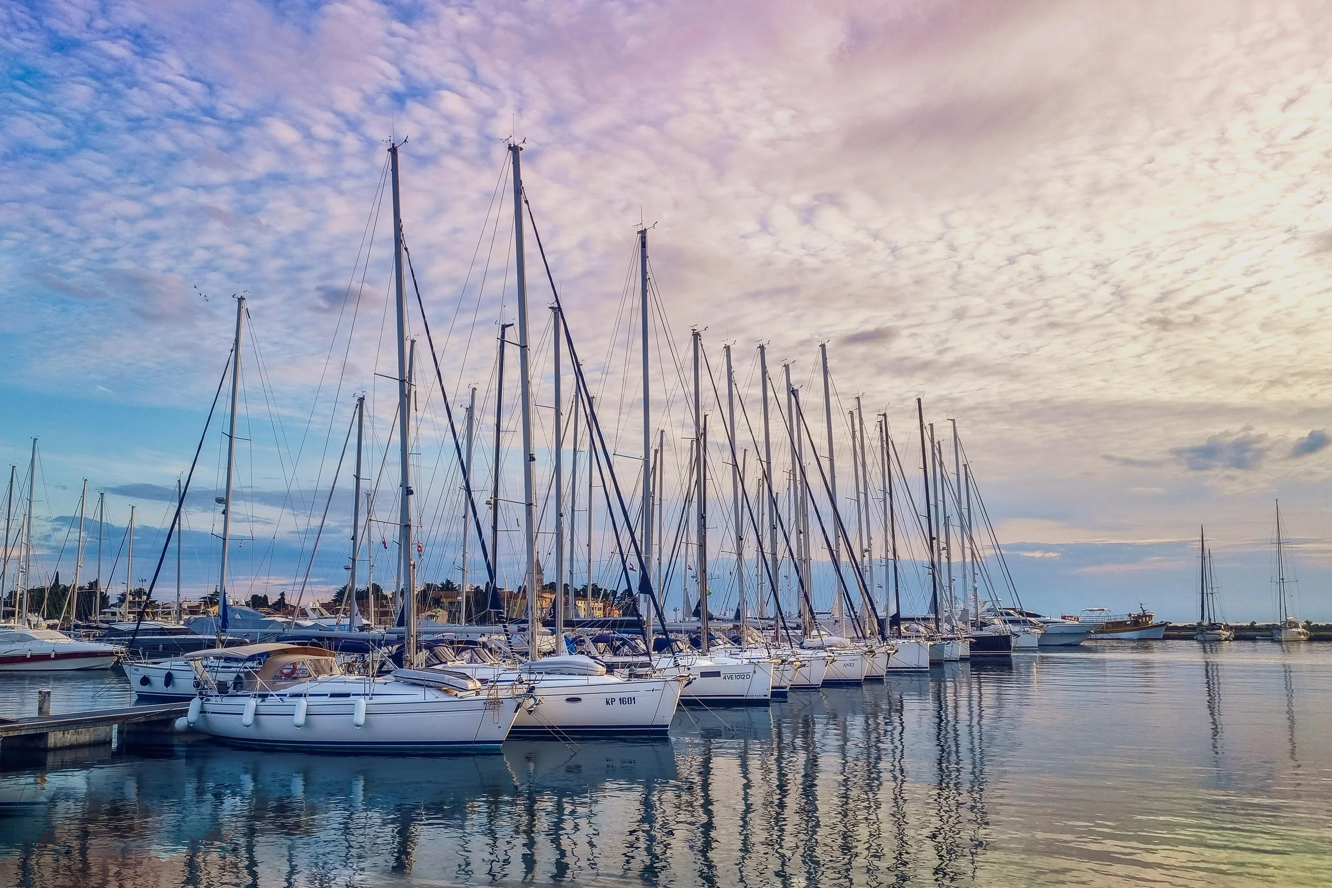 Sailboats moored at a marina under a pink and blue dusk sky