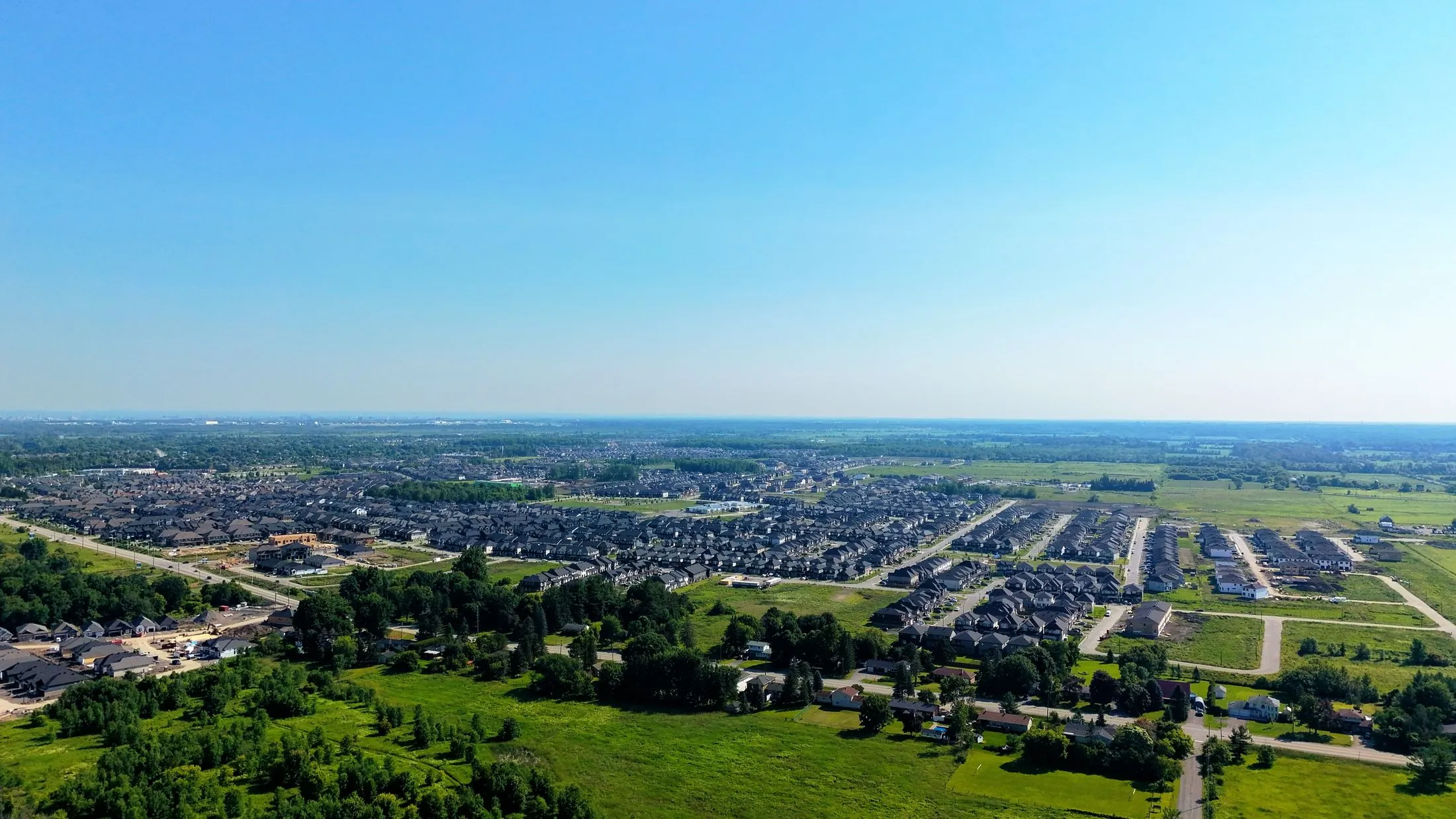 An aerial view of a residential suburb surrounded by green fields