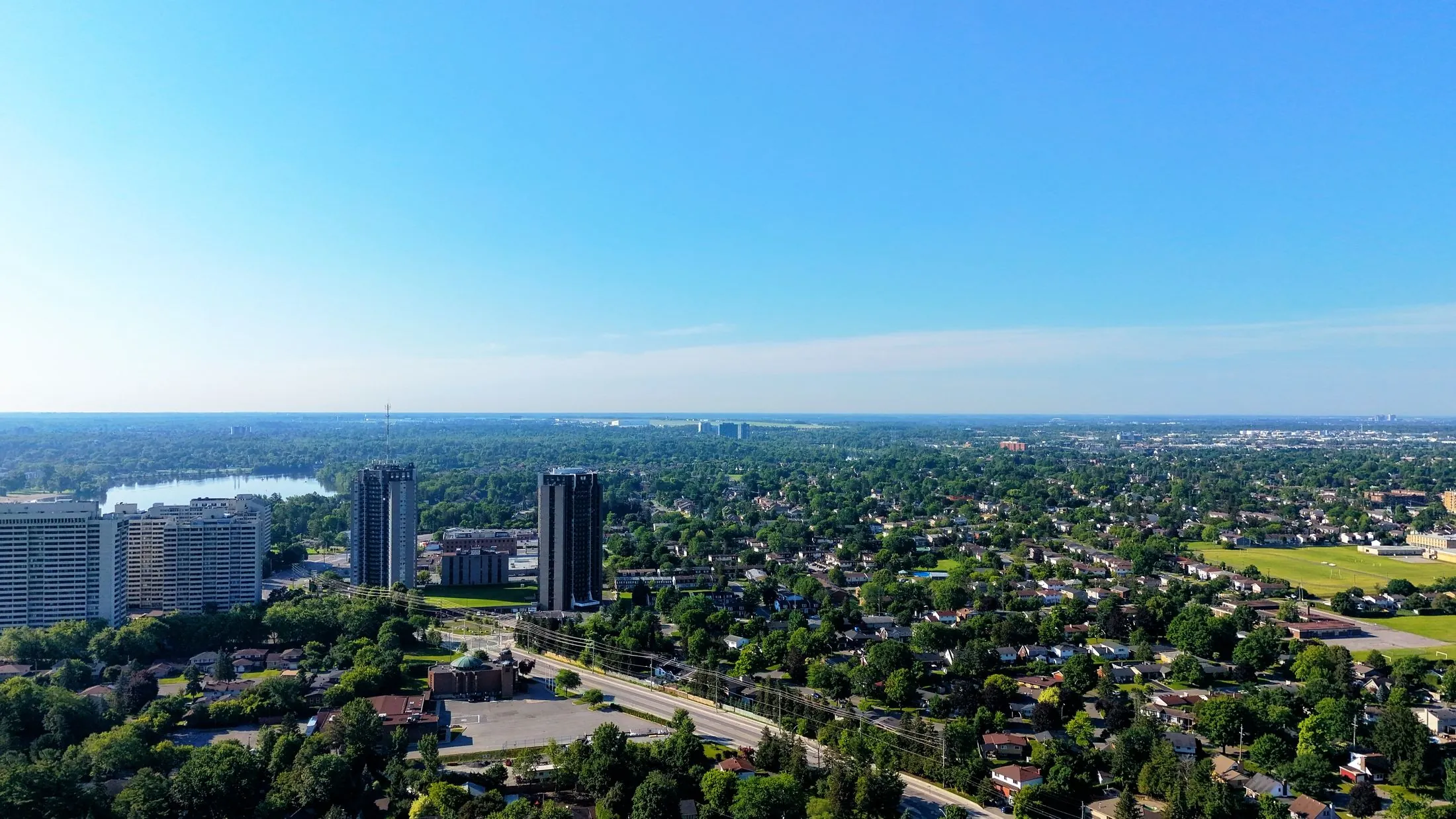 An aerial view of a suburban city with a few towers rising out of the trees