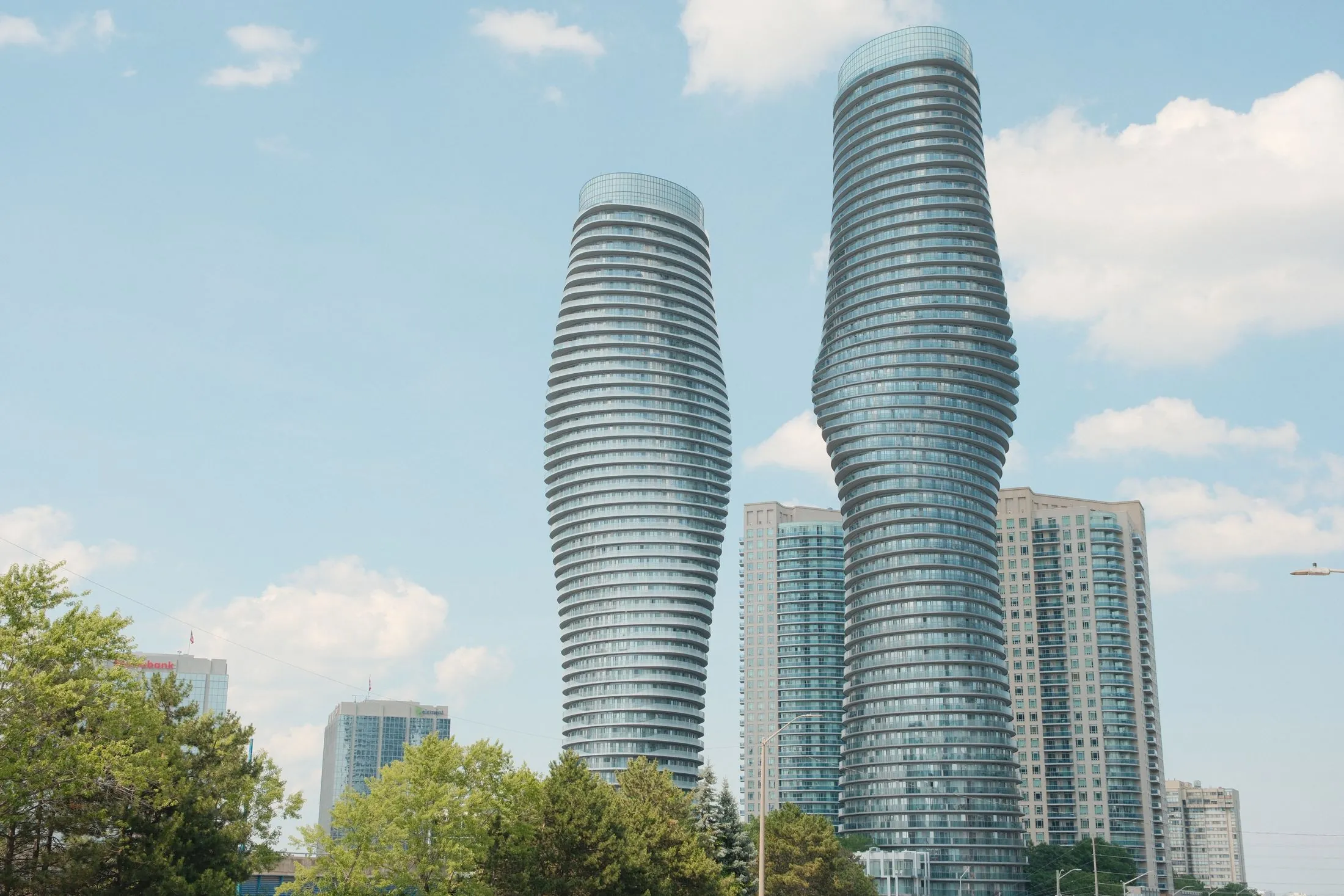 The curving Absolute World towers in Mississauga against a blue sky