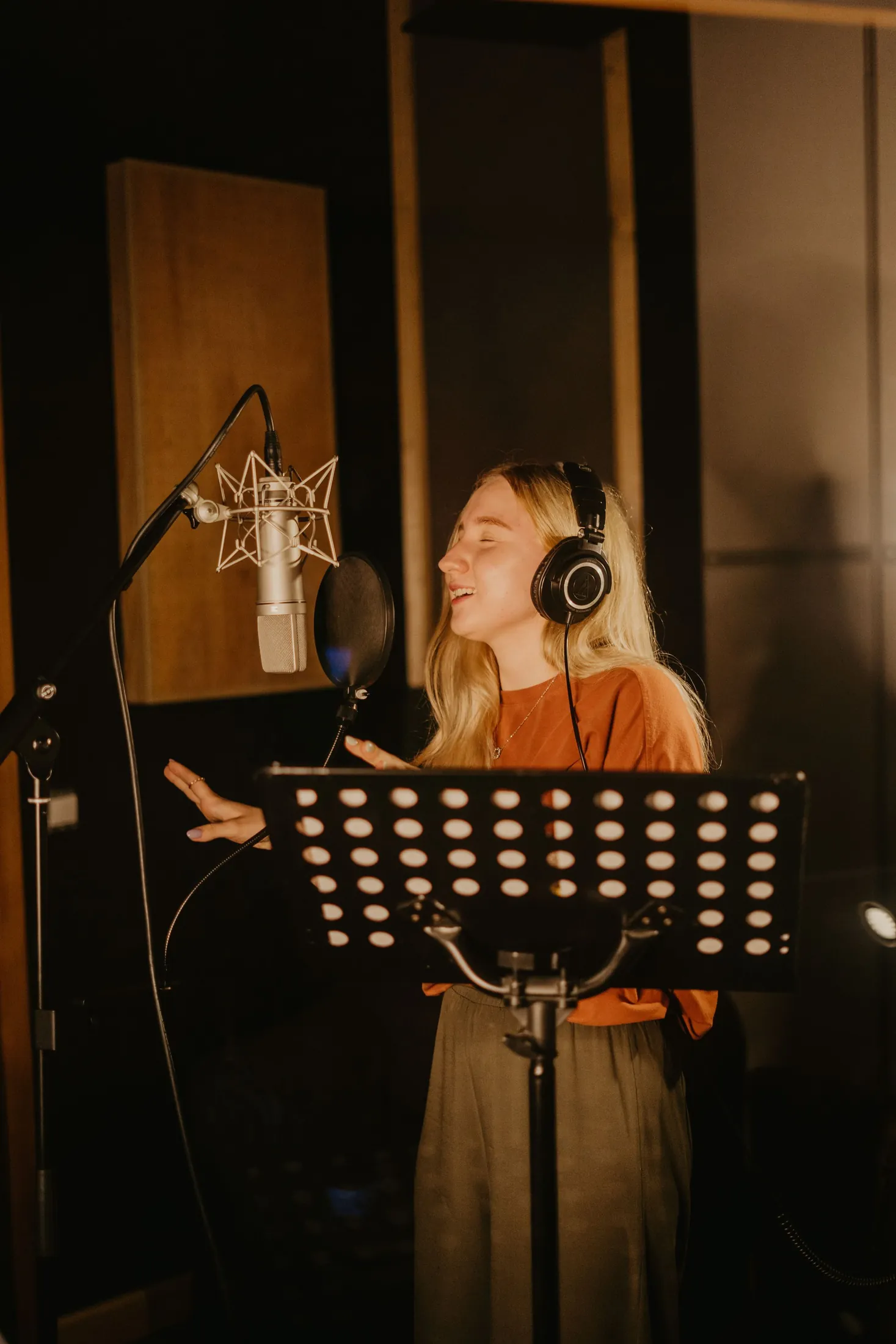 A singer in headphones recording at a microphone