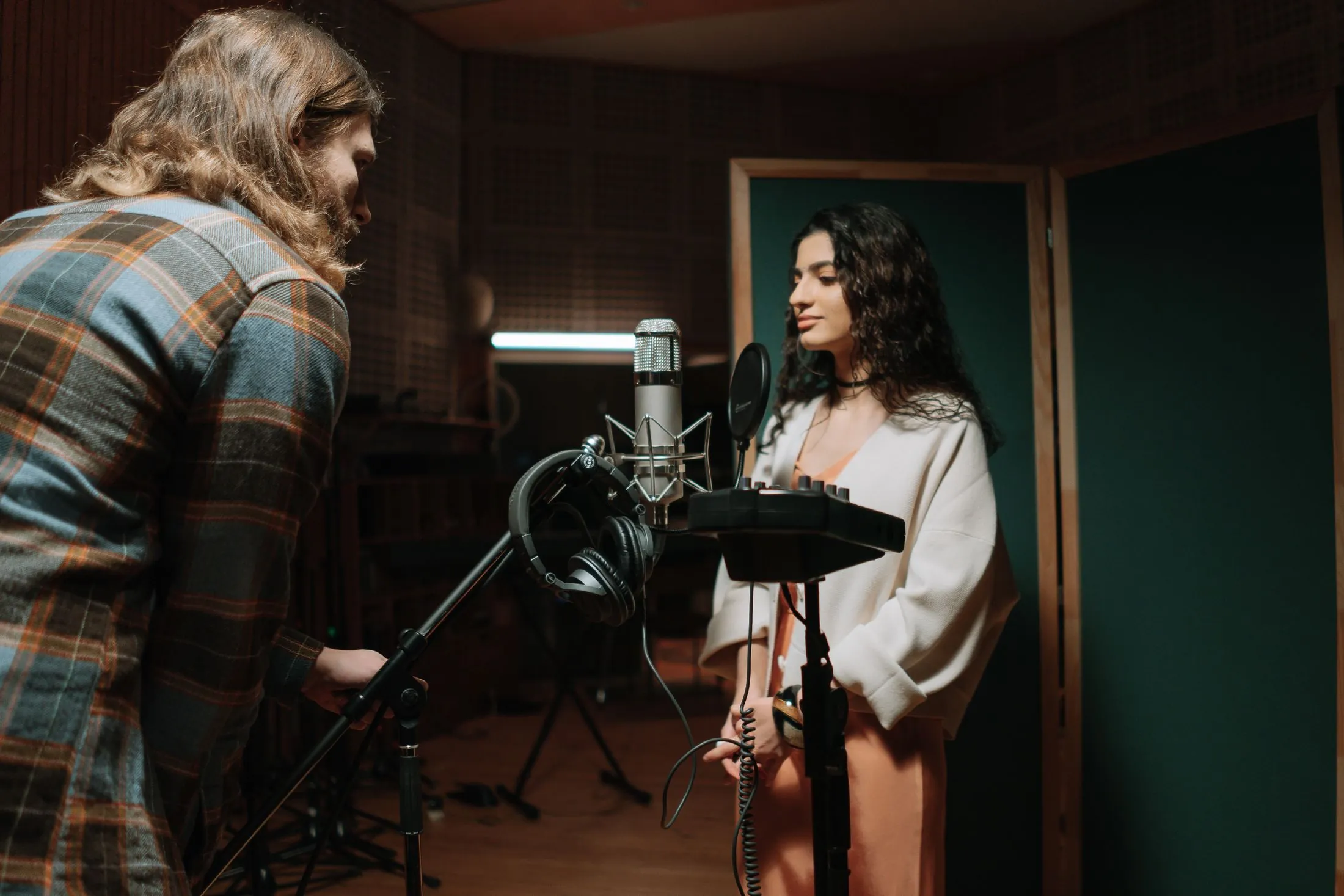 A singer recording vocals in a studio while a producer listens