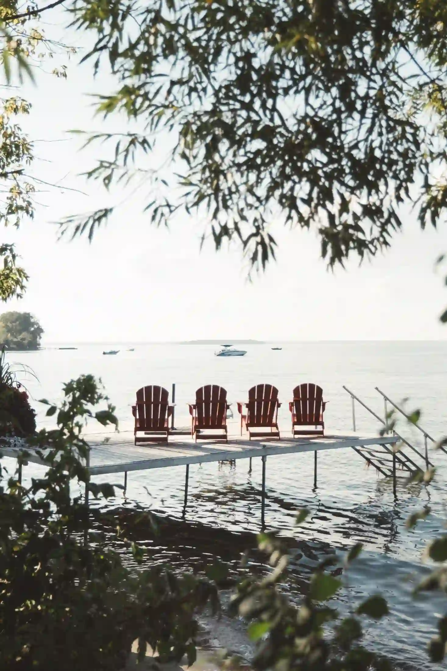 Red Muskoka chairs on a dock overlooking the lake near Orillia