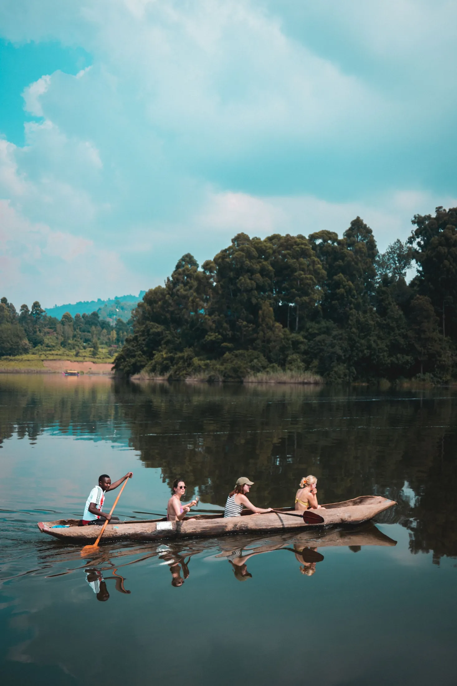 Four people paddling a canoe on a lake surrounded by forest