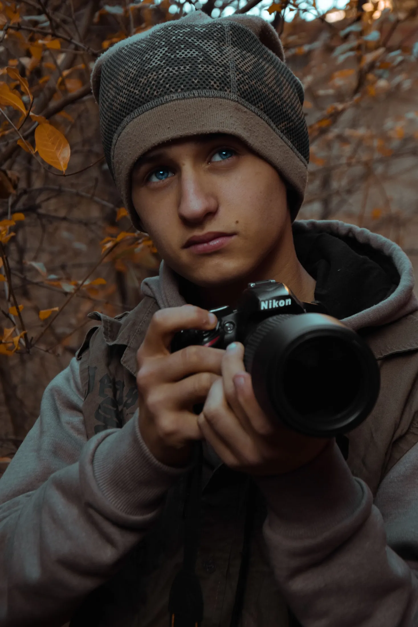 A young photographer holding a camera in an autumn forest