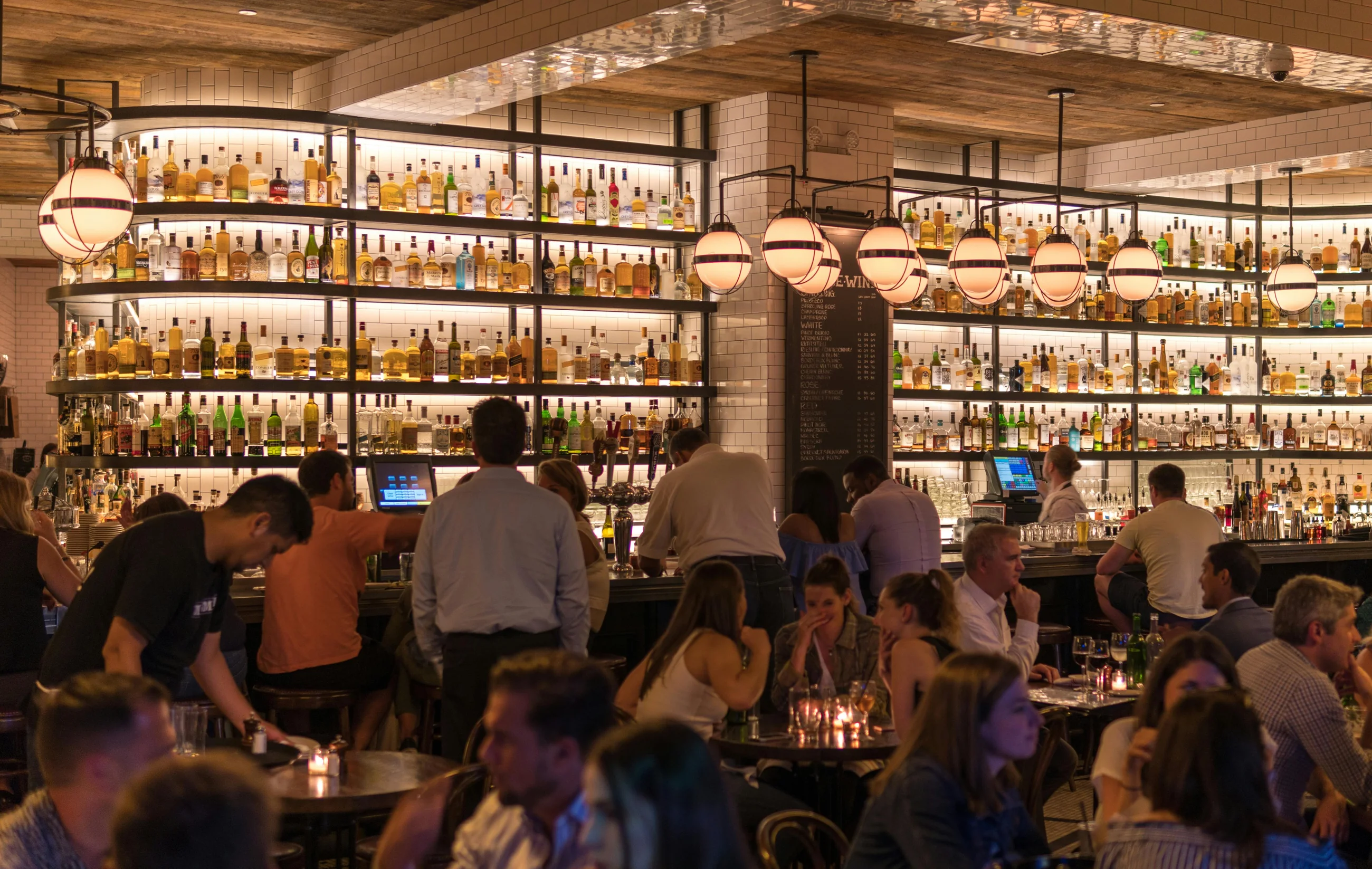 A busy restaurant bar at night, warm light over a full room of diners