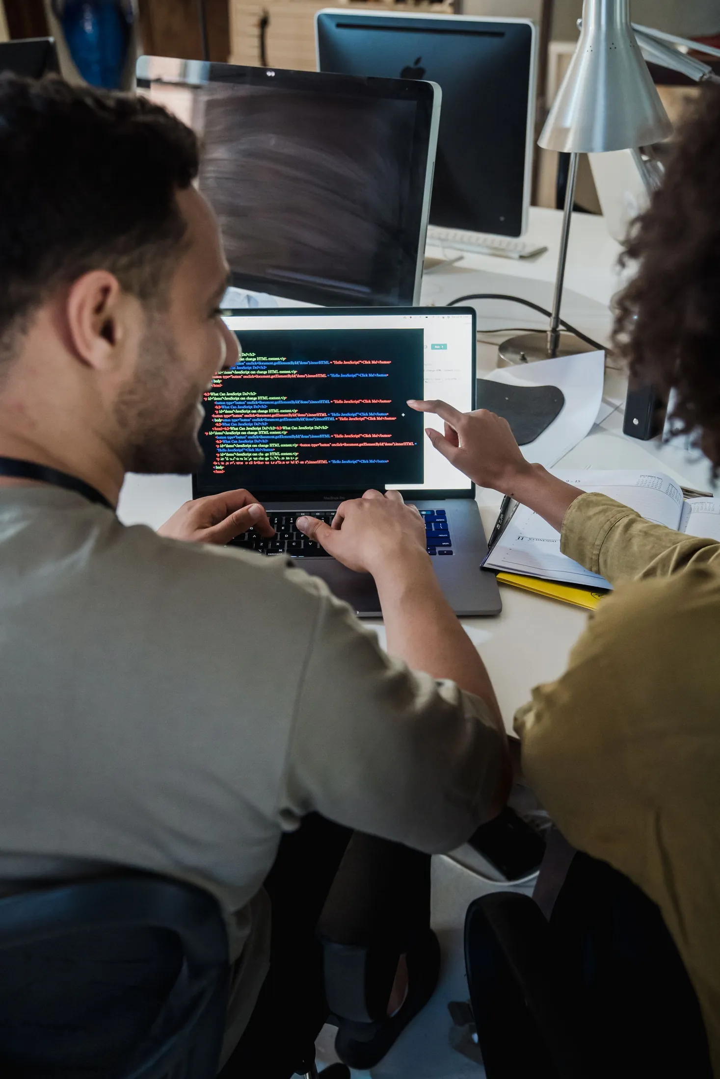Two developers talking through code on a laptop