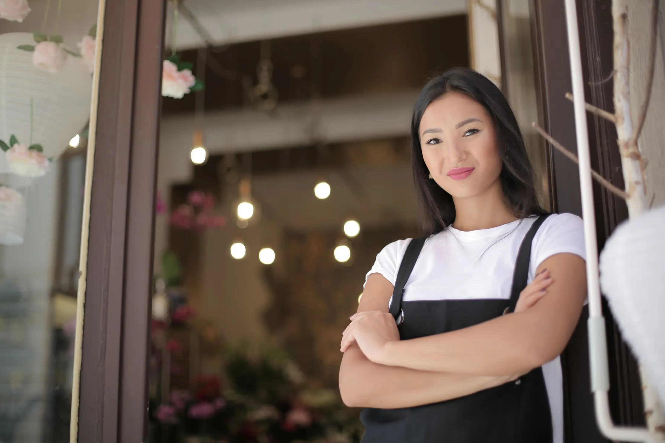 A florist standing with her arms crossed at the entrance of her shop