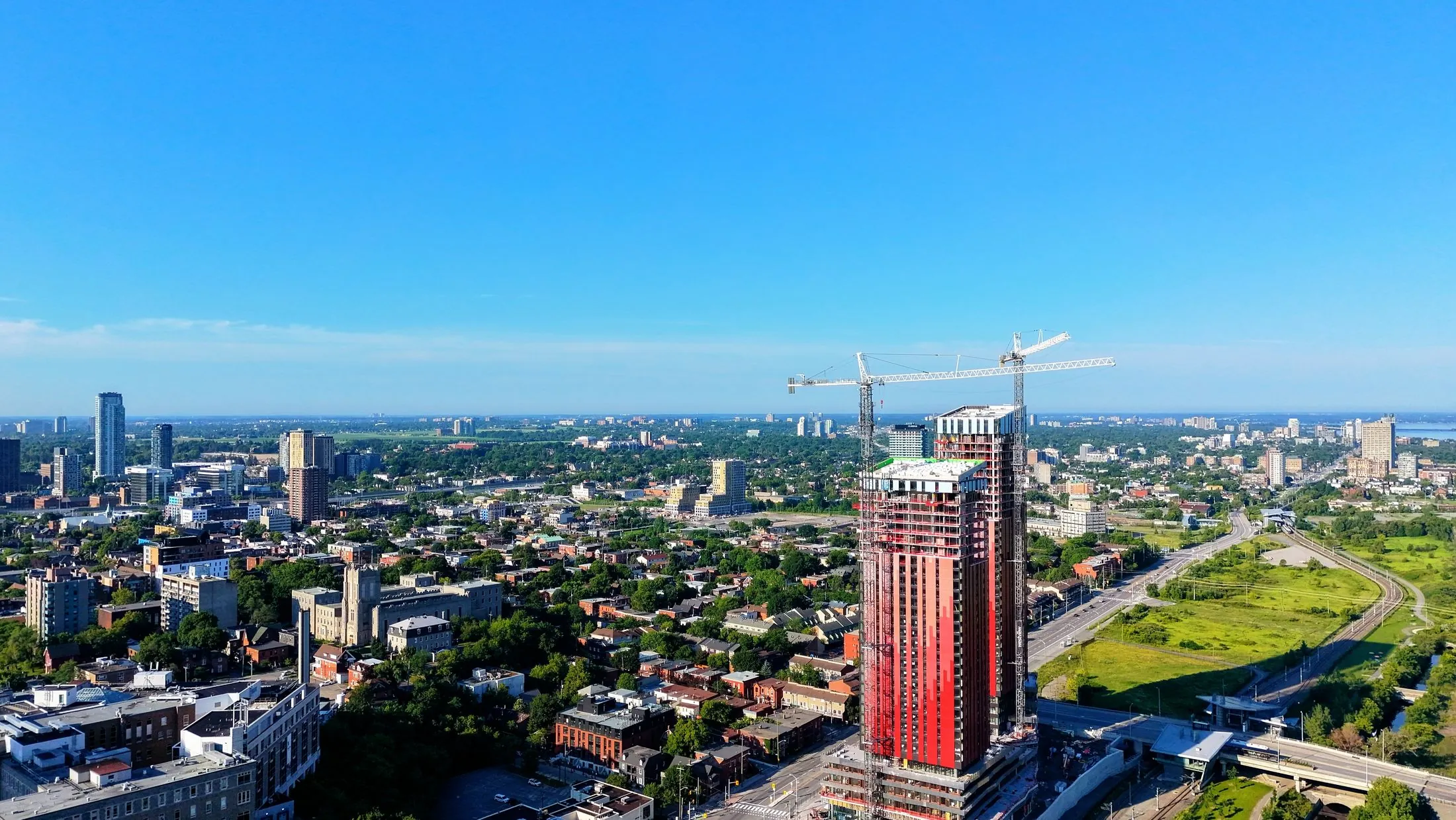 A new tower rising above the city, with construction cranes beside it