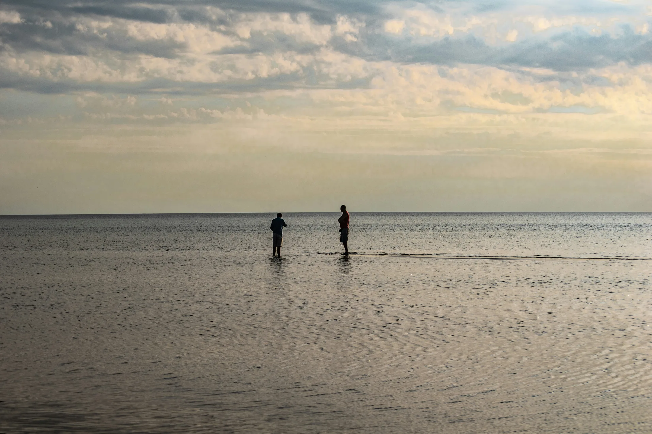 Two people wading in calm water at dusk on Georgian Bay