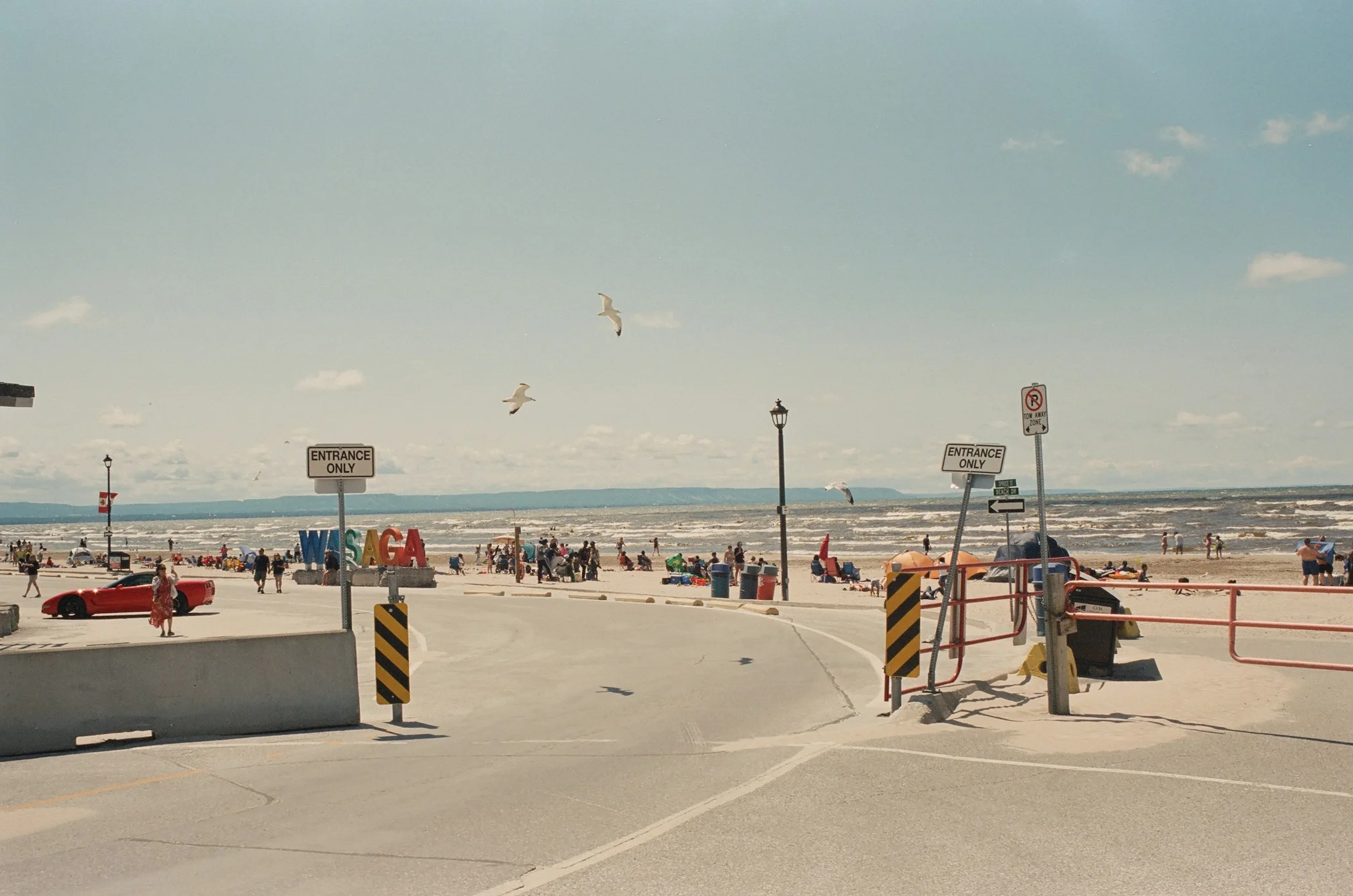 The WASAGA beach-entrance sign with crowds and Georgian Bay beyond