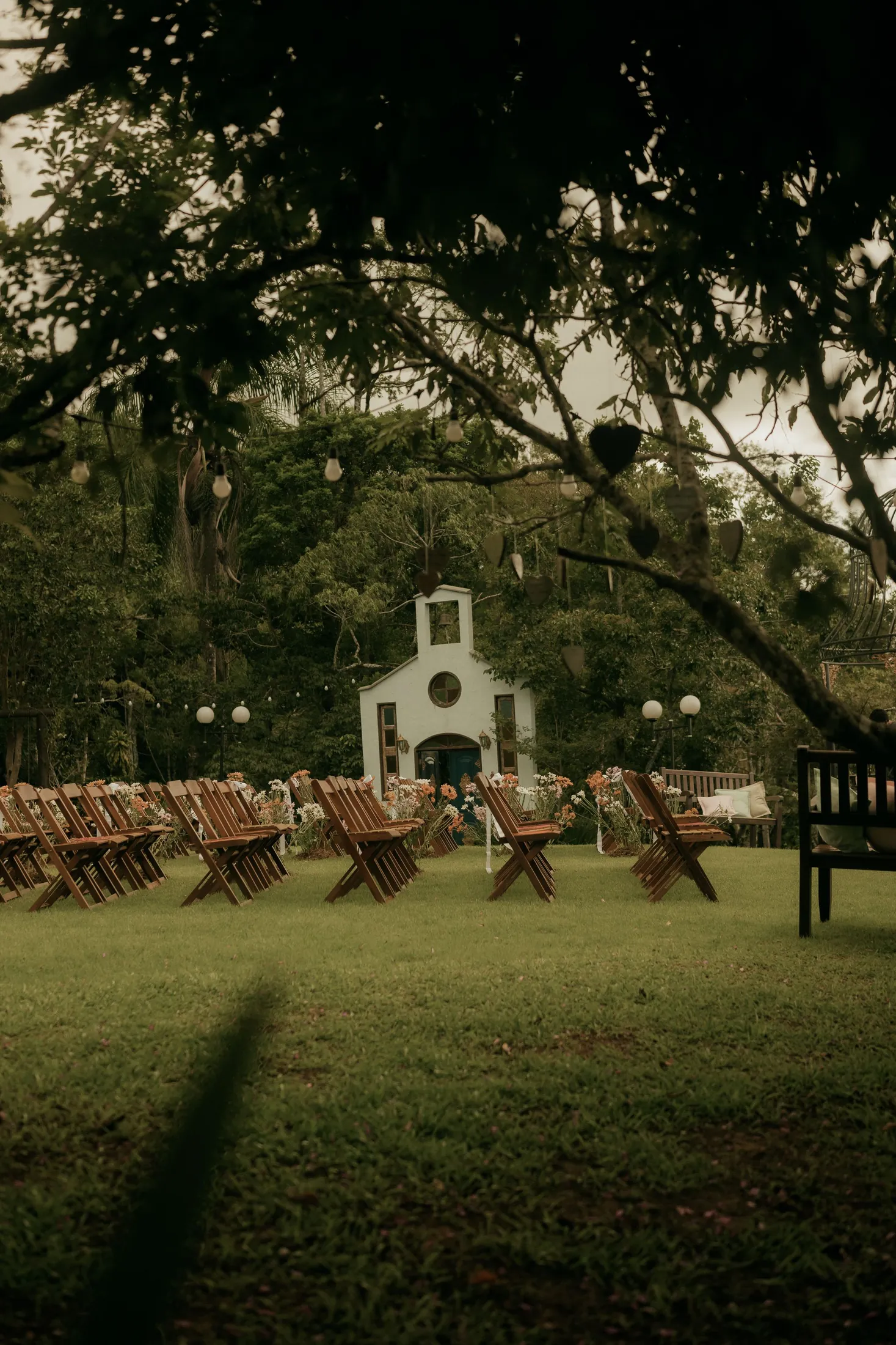 An outdoor wedding venue with wooden chairs set out in front of a small white chapel